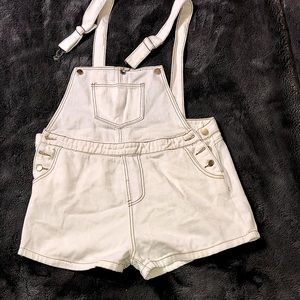 Cream denim overalls with brown buttons and brown stitches